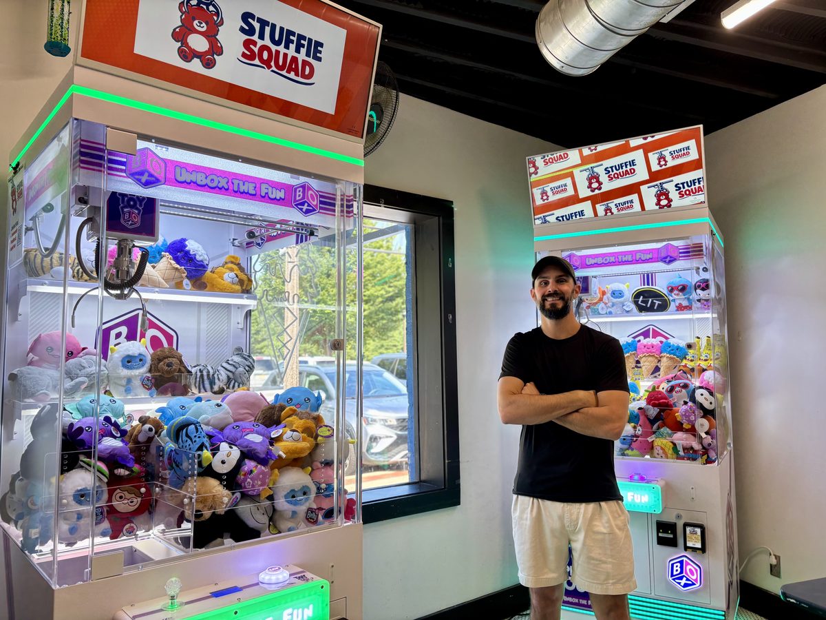 Chris standing beside two Stuffie Squad claw machines